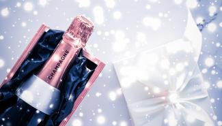 Champagne bottle and gift box on blue holiday glitter (Photo: Anneleven/stock.adobe.com)